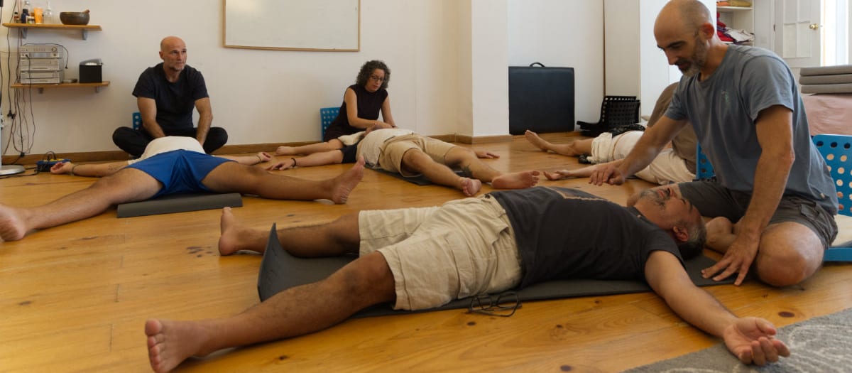 Sesión de trabajo corporal en el suelo de la sala, con el grupo tumbado y acompañamiento del terapeuta
